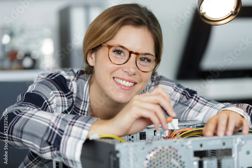 happy woman in glasses at table with broken processor