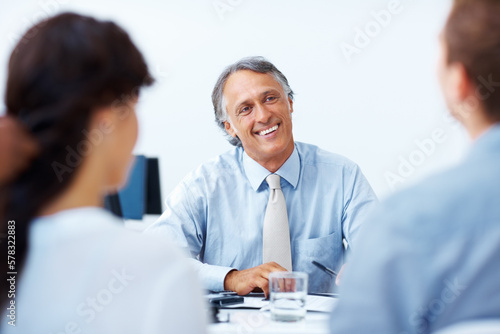 Male advisor discussing with clients in office. Happy mature advisor having discussion with clients in office.