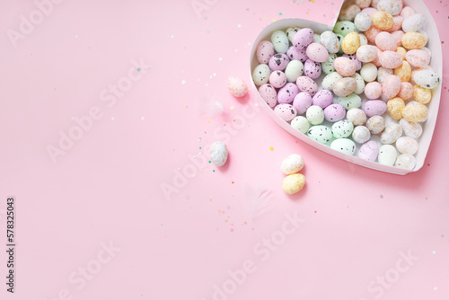 Photography heart shaped box filled with easter eggs on a pastel pink background with confetti