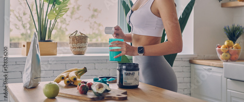 Close-up of sporty woman preparing protein cocktail in the kitchen