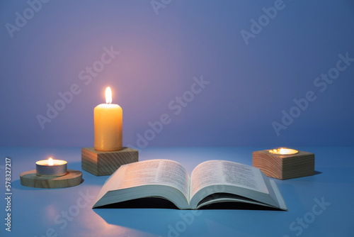 Christian Holy Bible with candles flame on blue background