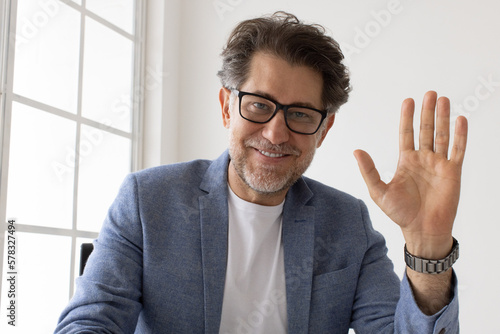 Senior business man waving to his colleagues on a video call photo