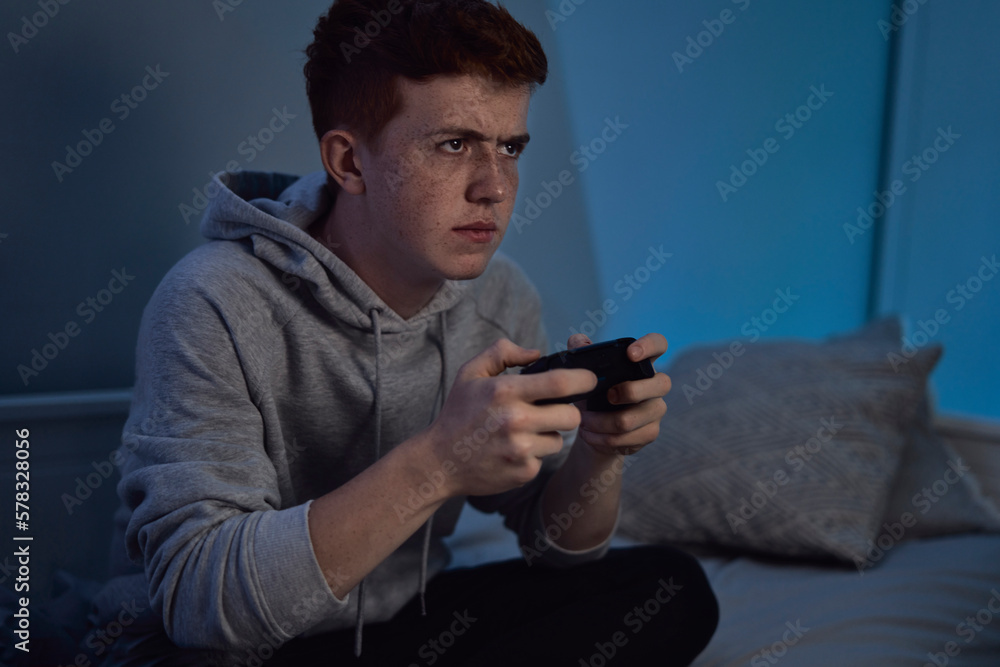 Caucasian teenage boy playing on game controller at night Caucasian teenage boy playing on game controller at night