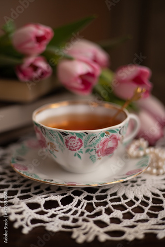 Photo of a cup of tea with a bouquet of flowers.