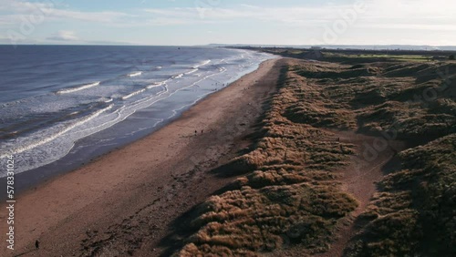 Drone flies back and slowly descends over dunes on a spectacular beach in County Durham, England   photo
