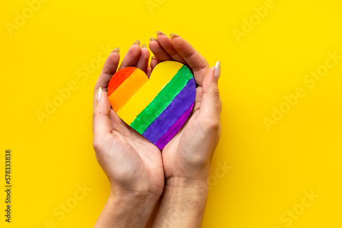 Female hands with rainbow LGBT colored heart paper cut. LGBT social rights concept.