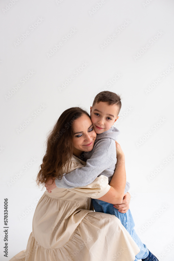  Boy preschooler and mother smile and hug on gray background in photo studio