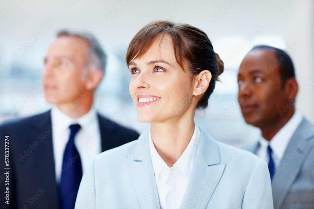 Female executive looking towards future. Focus on business woman with colleagues in distance. Female executive looking towards future. Focus on business woman with colleagues in distance.