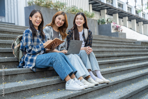 A group of young Asian female students who enjoy searching for scientific information on the field meets together to discuss and record in a notebook together.