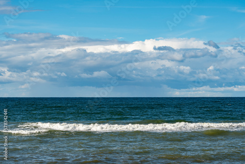 Panorama of a calm sea with clouds on the horizon. Background on the theme of summer vacation and ecology. Crystal clear ocean water. © Николай Батаев