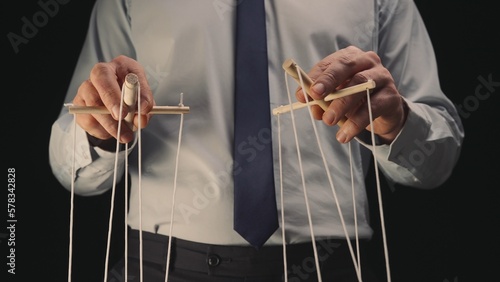 Tableau sur toile A businessman in a gray shirt and black tie controls a puppet with a wooden manipulator and strings