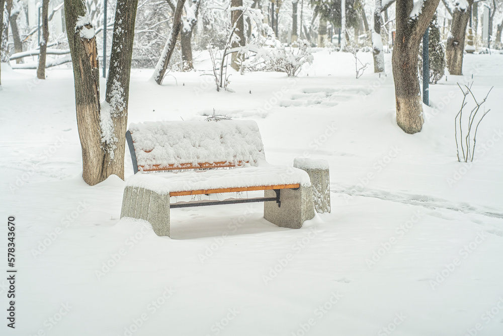 Empty bench covered with snow. Winter park in calm weather. Empty bench covered with snow. Winter park in calm weather.