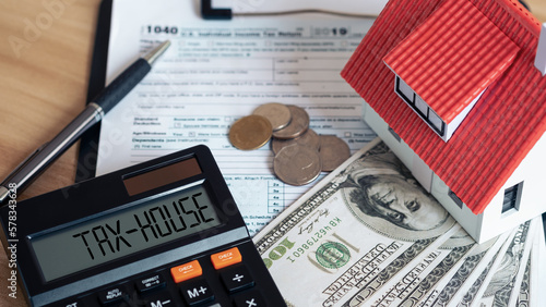 Tax house on calculator and Miniature house with money on tax papers. The concept of paying tax for housing and property. Debt payment. Property taxes. Tax house concept.