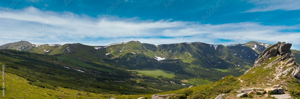 Summer mountain view with snow and big stones on mountainside.