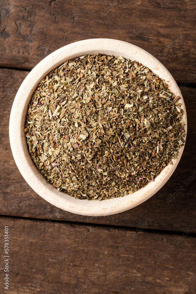 Dried basil leaves in bowl on wooden table. Close up. Top view Dried basil leaves in bowl on wooden table. Close up. Top view