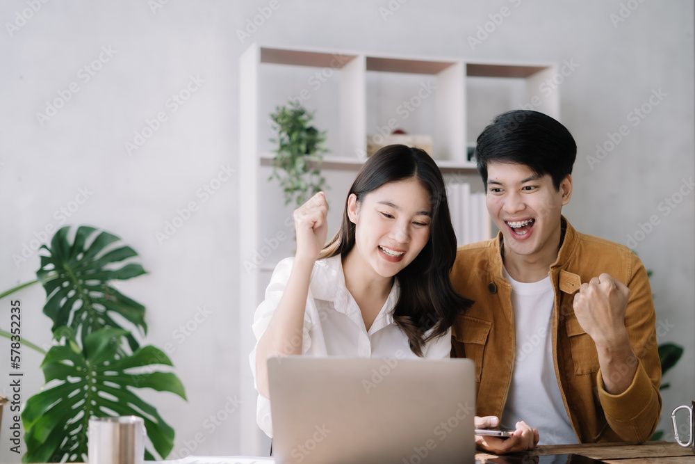 Asian couple looking laptop with happy together in the home. Success of lovers in front of a notebook. Happy couple on social online with a laptop. Asian couple looking laptop with happy together in the home. Success of lovers in front of a notebook. Happy couple on social online with a laptop.