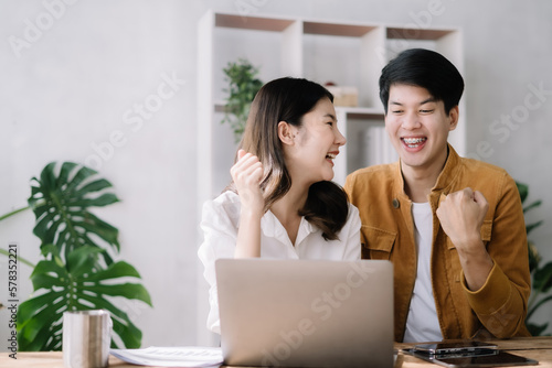 Asian couple looking laptop with happy together in the home. Success of lovers in front of a notebook. Happy couple on social online with a laptop.