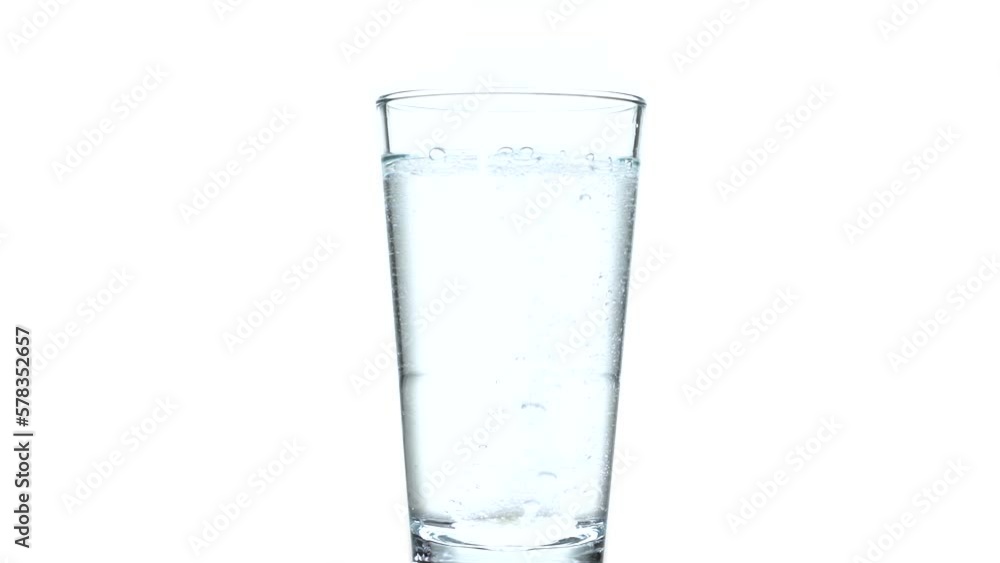 Fizzy tablet in glass of water isolated on white. Effervescent tablet dropped into the water Fizzy tablet in glass of water isolated on white. Effervescent tablet dropped into the water