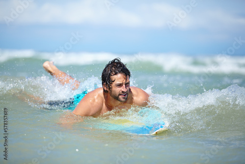 Waiting for the next big wave. An attractive young man waiting for a wave on his board in the ocean. © Marine Gastineau/peopleimages.com