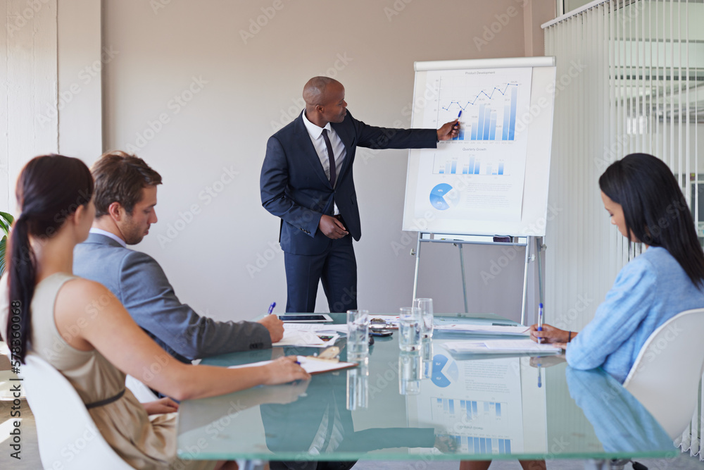 Pointing out their progress. a business manager presenting financial data to his colleagues during a meeting.