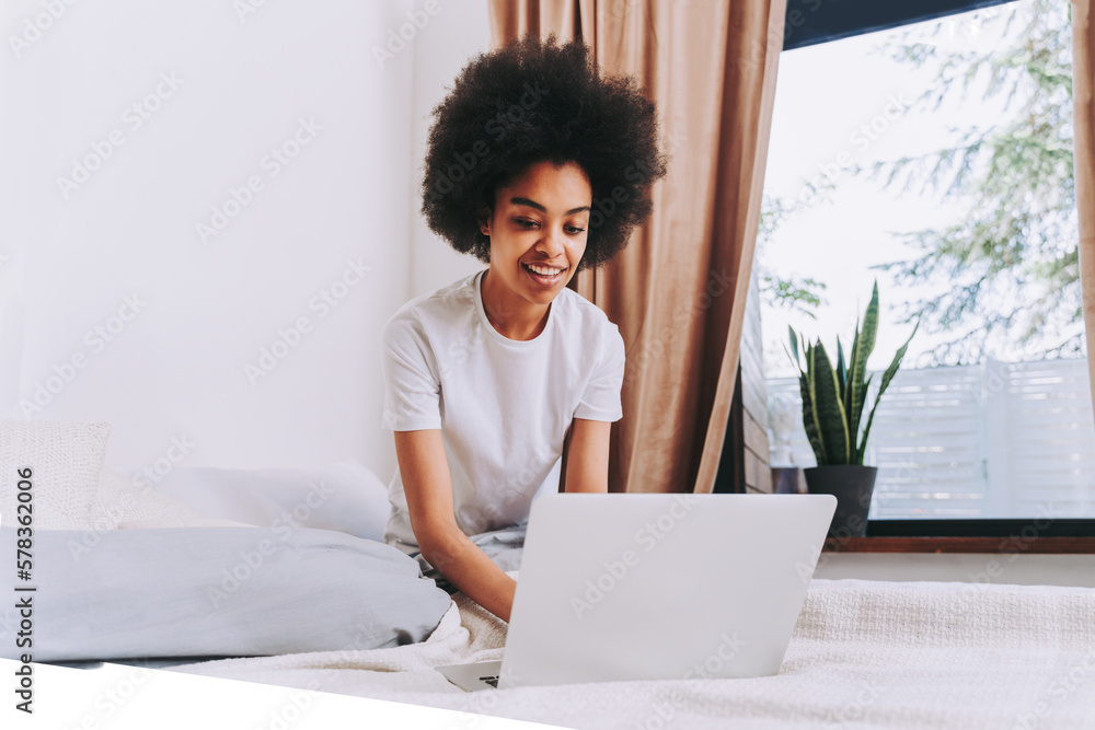 Afro american girl using computer laptop in bed at home Afro american girl using computer laptop in bed at home