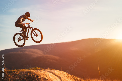 Young man on a mountain bike performing a dirt jump