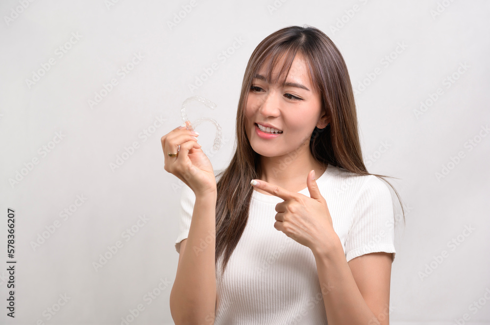 Young smiling woman holding invisalign braces over white background studio, dental healthcare and Orthodontic concept.. Young smiling woman holding invisalign braces over white background studio, dental healthcare and Orthodontic concept..