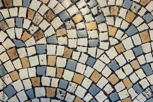 Vintage mosaic flooring fragment. Small squares in white  blue and yellow stone with black grout.