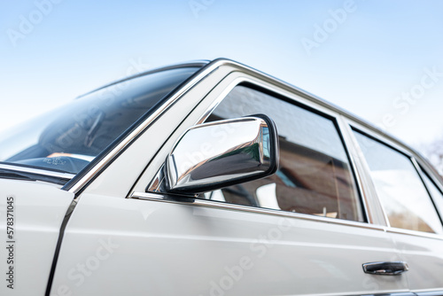 Low angle view of a chrome side mirror of a white car against a blue sky © Alex Marc Wagner