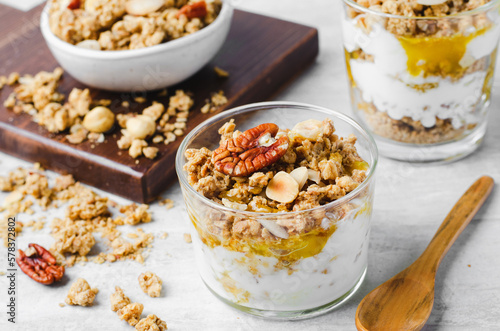 Granola and Yogurt Parfaits, Healthy Breakfast or Snack, Muesli with Nut Mix and Honey on Bright Concrete Background