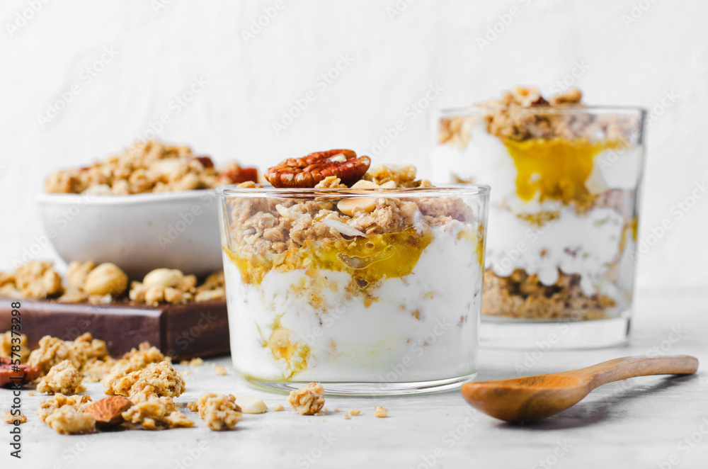 Granola and Yogurt Parfaits, Healthy Breakfast or Snack, Muesli with Nut Mix and Honey on Bright Concrete Background Granola and Yogurt Parfaits, Healthy Breakfast or Snack, Muesli with Nut Mix and Honey on Bright Concrete Background