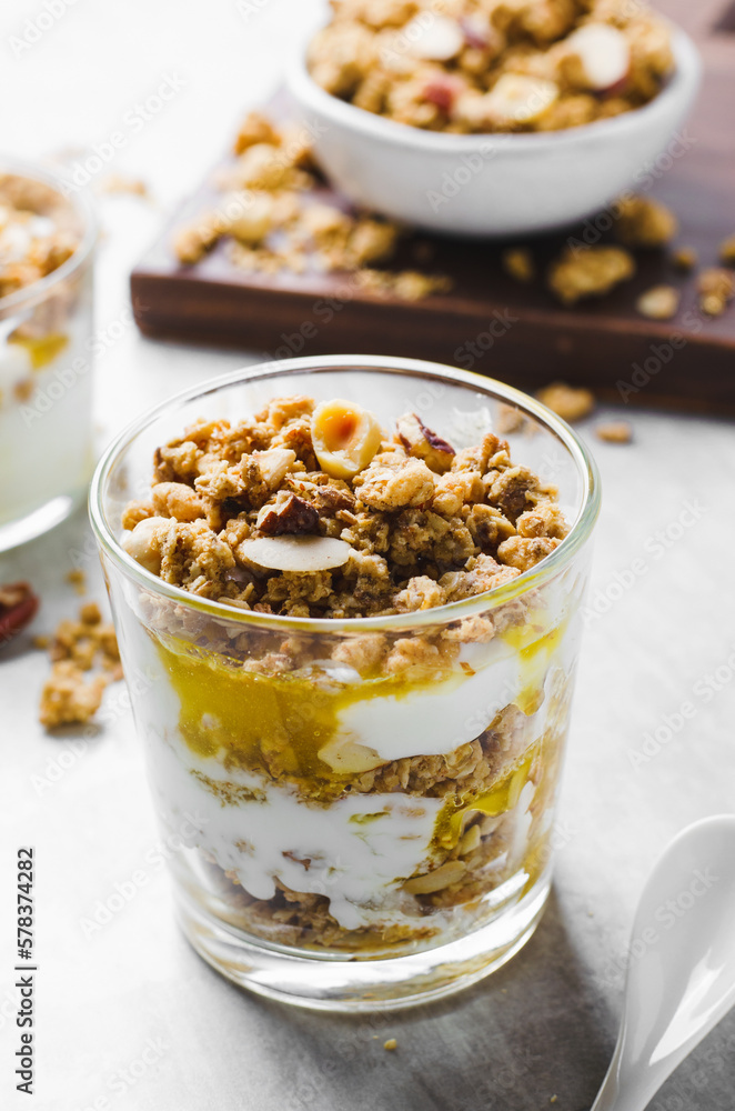 Granola and Yogurt Parfaits, Healthy Breakfast or Snack, Muesli with Nut Mix and Honey on Bright Concrete Background Granola and Yogurt Parfaits, Healthy Breakfast or Snack, Muesli with Nut Mix and Honey on Bright Concrete Background