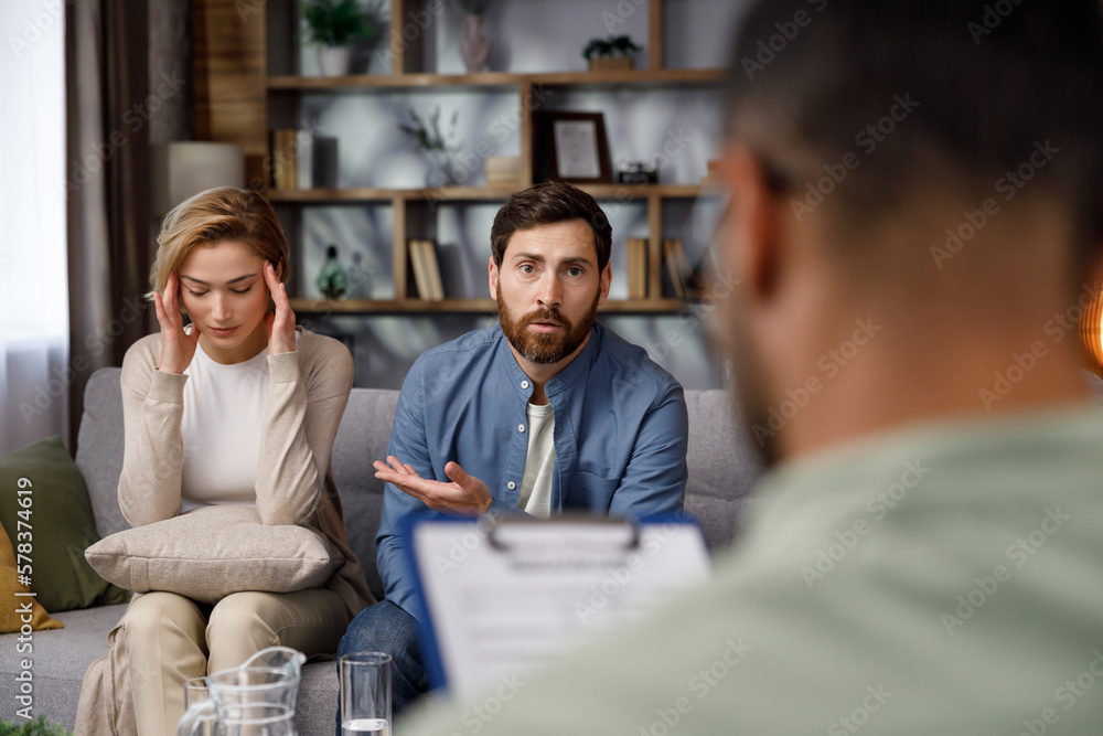 A quarrel between a husband and wife at a psychotherapist's appointment. A visit to a family psychologist for a married couple. An African-American doctor consults an unhappy couple. A quarrel between a husband and wife at a psychotherapist's appointment. A visit to a family psychologist for a married couple. An African-American doctor consults an unhappy couple.