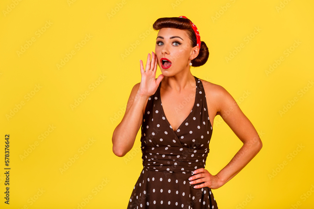 A cute lady in a polka dot dress with a retro hairstyle and red lipstick says something on a yellow background. A pin-up look with a modern twist. Vintage party A cute lady in a polka dot dress with a retro hairstyle and red lipstick says something on a yellow background. A pin-up look with a modern twist. Vintage party