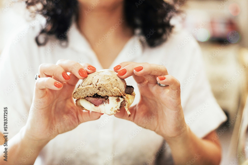 Woman's hands holding a sandwich with bred, cheese and medium done steak - traditional Portuguese meal 