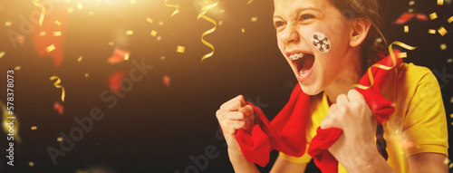 Vászonkép Young girl emotionally watching football match, cheering up favorite team over dark background with confetti