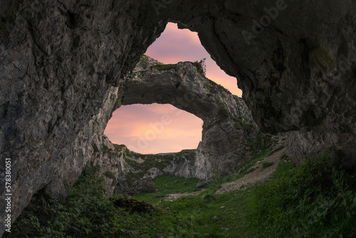 Double hole cave in mountainous terrain against sunset sky photo