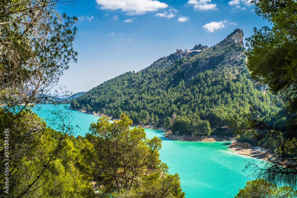 Obraz premium Lake Guadalest, rocky mountains and hills covered with trees. Blue sky