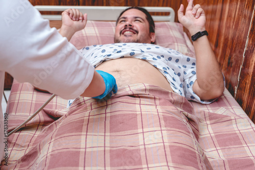A male patient feels tickled from a abdominal ultrasound procedure. Feeling the gentle pressure of the transducer and coolness of the gel. photo