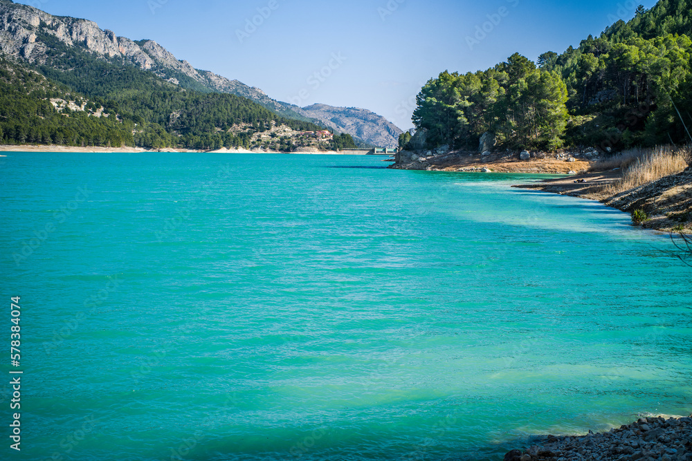 Fototapeta premium Lake Guadalest, rocky mountains and hills covered with trees. Blue sky