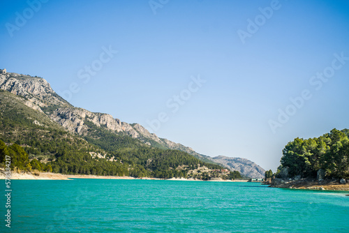 Lake Guadalest  rocky mountains and hills covered with trees. Blue sky