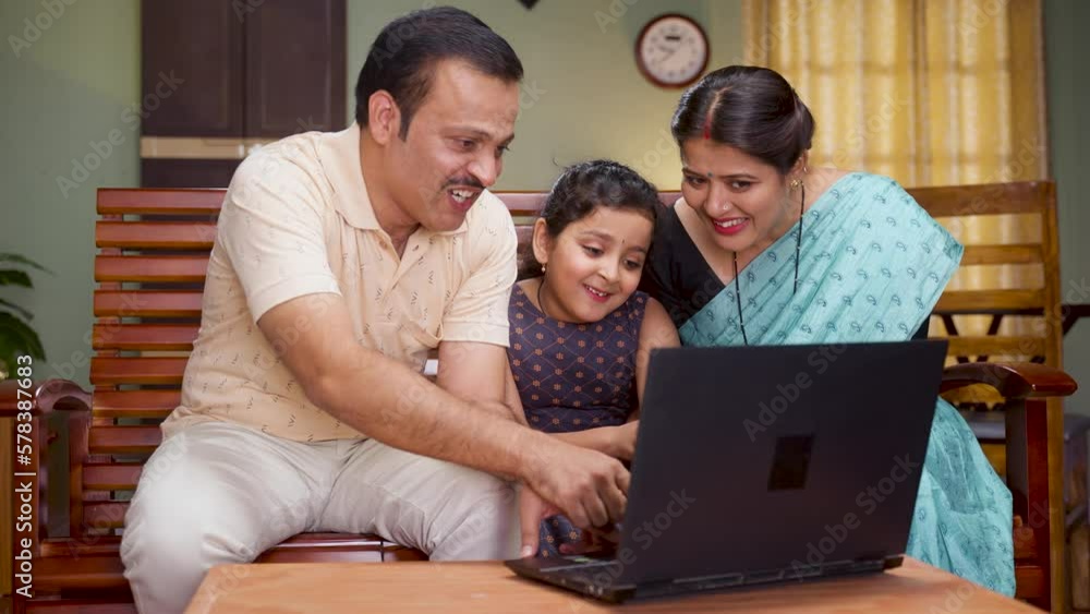 Happy smiling couple with daughter watching laptop while sitting on sofa at home - concept of technology, weekend holidays and relaxation Happy smiling couple with daughter watching laptop while sitting on sofa at home - concept of technology, weekend holidays and relaxation