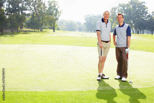 Two golfers smiling. Full length of two men standing on golf course and smiling.