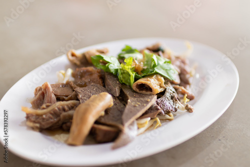 Boiled beef offal serve in a plate with dipping sauce.
