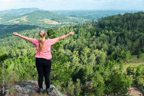 happy female hiker enjoying the view from the mountain top in the forest
