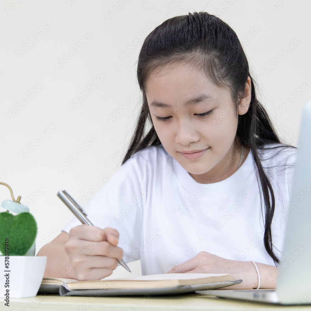 Asian girl is studying online via the internet with a cheerful smile, stay home, New normal, Covid-19 coronavirus, Social distancing, Internet learning. Asian girl is studying online via the internet with a cheerful smile, stay home, New normal, Covid-19 coronavirus, Social distancing, Internet learning.