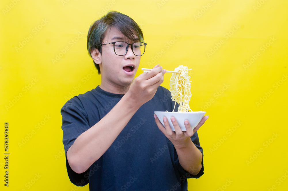 Happy attractive asian man with peek a boo hair eats noodles on bowl with chopstick Happy attractive asian man with peek a boo hair eats noodles on bowl with chopstick