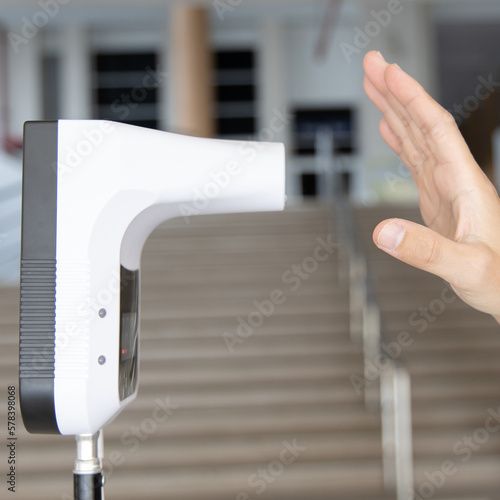 Young man used his palm to touch the sensor of the thermometer temperature using a non-contact infrared thermometer, Body temperature measurement device to prevent COVID-19 virus.