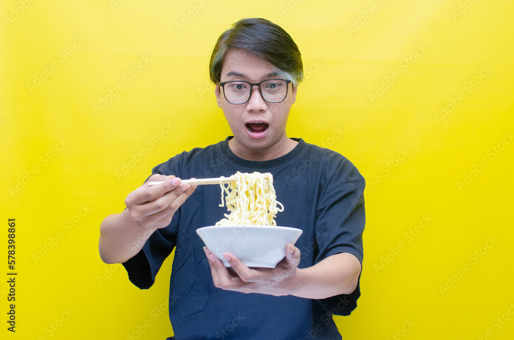 Happy attractive asian man with peek a boo hair eats noodles on bowl with chopstick Happy attractive asian man with peek a boo hair eats noodles on bowl with chopstick