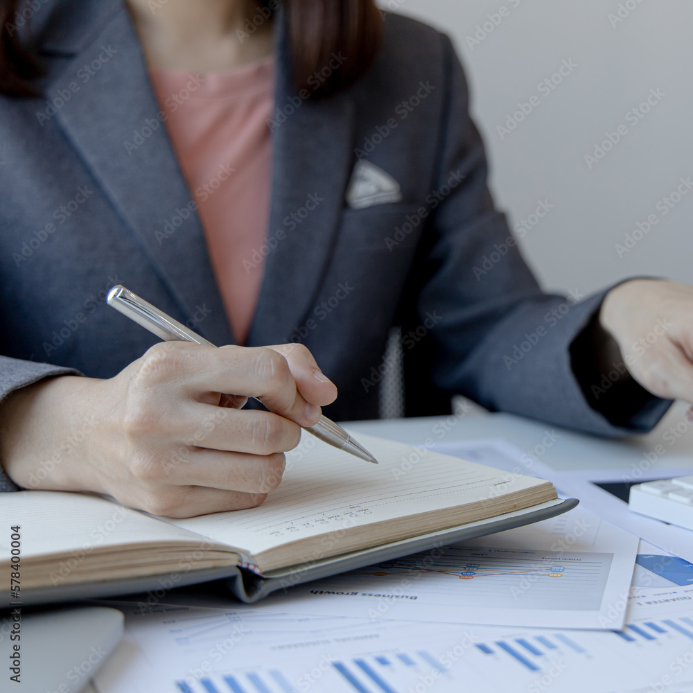 Head of accounting is recording the company's financial growth statistics using graphs as a reference for reviewing and analyzing the results, Taking notes and analyzing data graphs in office. - obrazy, fototapety, plakaty 